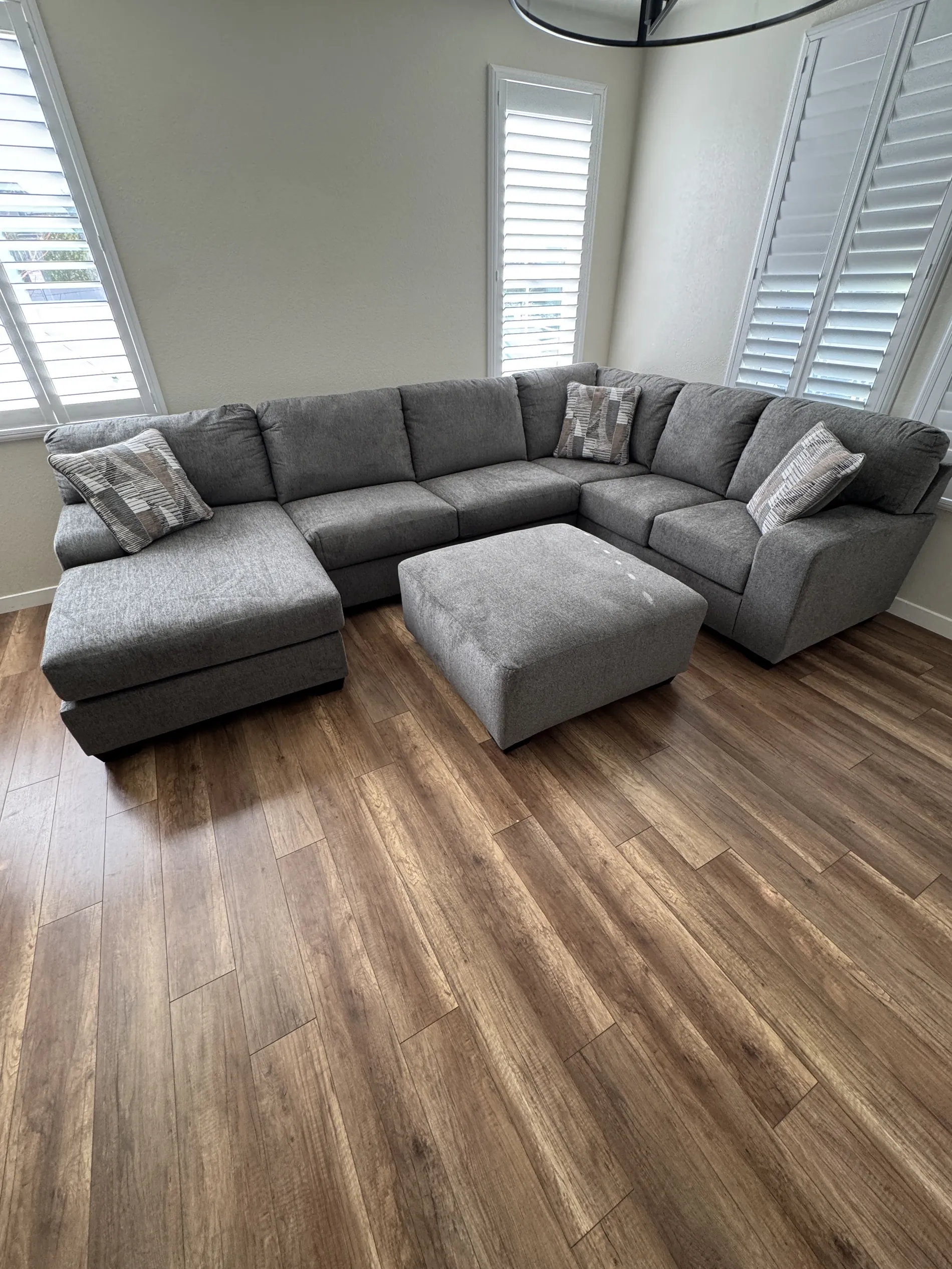 Grey channel sectional with ottoman styled by tall windows